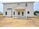 A covered back porch with white columns and a door to the backyard with straw covered ground at 236 Johnson Ridge Way, Four Oaks, NC 27524
