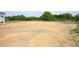 A spacious backyard with straw, trees, and partial view of the side of a home with natural landscaping at 236 Johnson Ridge Way, Four Oaks, NC 27524