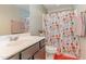 A bathroom with a white vanity, colorful shower curtain, and patterned towels at 2407 Cattail Pond Dr, Zebulon, NC 27597