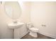 This half bathroom features a pedestal sink, circular mirror, and wood-look flooring at 247 Johnson Ridge Way, Four Oaks, NC 27524