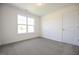 This carpeted bedroom features white walls, a window, and a door at 247 Johnson Ridge Way, Four Oaks, NC 27524