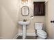 Well-lit half bathroom with pedestal sink, decorative mirror, and dark wood cabinetry above the toilet at 347 Country Mill Way, Fuquay Varina, NC 27526
