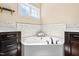 Bright bathroom featuring a soaking tub surrounded by dark cabinetry and decorative tile backsplash at 347 Country Mill Way, Fuquay Varina, NC 27526