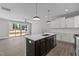Open-concept kitchen with dark cabinets, stainless appliances, and a large island overlooking the backyard at 608 Marshskip Way, Rolesville, NC 27587