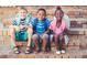 Three smiling school children with backpacks sitting on brick steps near a school or community building at 9164 Dupree Meadow Dr # 14, Angier, NC 27501