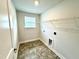 Laundry room with gray tile floor, a window, shelving and washer/dryer hookups at 111 Southern Estates Dr, Sanford, NC 27330
