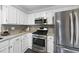 Updated kitchen with stainless steel appliances, granite countertops, and white cabinetry at 210 W Oak Ave, Wake Forest, NC 27587