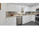 Well-lit kitchen with white cabinets, granite countertops, and stainless steel appliances at 210 W Oak Ave, Wake Forest, NC 27587