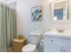 Bright bathroom featuring a white vanity, toilet, and shower with a light green curtain at 211 Long Ave, Graham, NC 27253