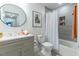 Bathroom features a large vanity, round mirror, and tiled shower and tub combination at 211 Long Ave, Graham, NC 27253