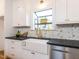 Bright kitchen featuring white cabinetry, black countertops, farmhouse sink, and stainless steel dishwasher at 211 Long Ave, Graham, NC 27253