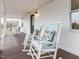 Inviting front porch featuring rocking chairs with stylish floral cushions and a dark stained wood deck at 211 Long Ave, Graham, NC 27253