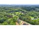 Aerial shot showcases property with a pond, houses, lush trees, and open green spaces, presenting a tranquil environment at 260 Ellington Rd, Graham, NC 27253