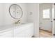 Bathroom featuring a round mirror, vanity, and entrance to the toilet with natural light at 260 Ellington Rd, Graham, NC 27253