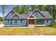 Beautiful blue home with red accents, a covered front porch, black mulch, and a lush green lawn at 260 Ellington Rd, Graham, NC 27253
