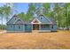Inviting blue two-story home boasts stylish architectural details and a covered front porch with finished yard at 260 Ellington Rd, Graham, NC 27253