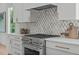 Gas range with decorative backsplash, white cabinetry, and stainless steel details at 324 Waldo St, Cary, NC 27511