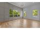 Bright living room features large windows, modern chandelier, paneled accent wall, and hardwood floors at 324 Waldo St, Cary, NC 27511