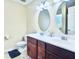 Bathroom with double sinks, wood cabinets, oval mirrors, and tile flooring provides style and function at 4809 Kaycee Ct, Raleigh, NC 27616