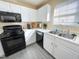 Kitchen with white cabinets, modern black appliances, and gray flooring at 4809 Kaycee Ct, Raleigh, NC 27616