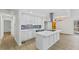 Bright kitchen features white cabinets, an island with cooktop, and modern stainless steel range hood at 5709 Russell Rd, Durham, NC 27712