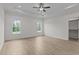 Spacious room featuring recessed lights, ceiling fan, two windows, and light wood floors at 6294 River Rd, Fuquay Varina, NC 27526
