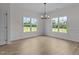 Sunlit dining room with large windows and elegant chandelier fixture at 6294 River Rd, Fuquay Varina, NC 27526