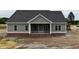 New construction featuring a covered front porch and gray siding over a brick foundation at 6294 River Rd, Fuquay Varina, NC 27526