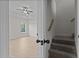 Inviting hallway leading to a tiled living area, with carpeted stairs and wood railing at 6294 River Rd, Fuquay Varina, NC 27526