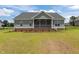 Rear exterior view of a gray home with a screened porch and a spacious yard at 6294 River Rd, Fuquay Varina, NC 27526