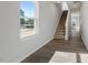 Hallway with neutral walls, wood floors, a window offering natural light, and a staircase leading upstairs at 103 Central Townes Way # 297, Raleigh, NC 27603