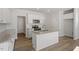 Bright kitchen features white cabinets, stainless steel appliances, granite countertops, a kitchen island and wood flooring at 103 Central Townes Way # 297, Raleigh, NC 27603