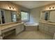 Large bathroom featuring a corner soaking tub below a large window and dual vanities at 112 Gingergate Dr, Cary, NC 27519