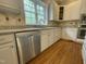 Well-lit kitchen with stainless steel appliances, white cabinets, granite counters, and a view of the wooded property at 112 Gingergate Dr, Cary, NC 27519