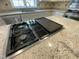 Close-up of a built-in cooktop on a kitchen island with granite countertops and stainless steel appliances at 112 Gingergate Dr, Cary, NC 27519