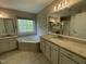 Bright main bathroom with double vanities, granite countertops, a jacuzzi tub, and natural light from the window at 112 Gingergate Dr, Cary, NC 27519
