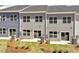 Exterior view of the back of townhomes with patios, sliding glass doors, and a green lawn at 115 Central Townes Way # 300, Raleigh, NC 27603