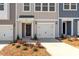Close up of a new home's front yard, featuring manicured landscaping, an attached garage, and a well-lit entry at 115 Central Townes Way # 300, Raleigh, NC 27603
