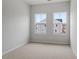 Neutral carpeted bedroom with white walls and a view of the neighbors' houses through 2 double paned windows at 116 Fideaux Blvd # 258, Raleigh, NC 27603