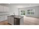 An open-concept kitchen with white cabinets, an island with sink, and stainless steel appliances flows into the dining area at 116 Fideaux Blvd # 258, Raleigh, NC 27603