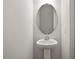 Neutral half-bathroom featuring pedestal sink, oval mirror, and blank white walls at 136 Fideaux Blvd # 253, Raleigh, NC 27603