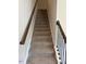 A carpeted staircase has wooden handrails and black metal balusters at 142 Vega Loop, Sanford, NC 27330