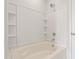 Bathroom featuring a soaking tub with white tile surround, built-in shelving, and chrome fixtures at 144 Fideaux Blvd # 251, Raleigh, NC 27603