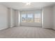 Spacious main bedroom with large windows, neutral carpet, ceiling fan, and views of neighborhood homes at 144 Fideaux Blvd # 251, Raleigh, NC 27603