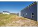 Side and back yards show ample grass and dirt area with the home's gray vinyl siding and white trim and windows at 30 Rosewood Ln, Youngsville, NC 27596