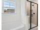 Bright bathroom with a shower and tub combo with black trim and fixtures under a clear window with a house view at 30 Rosewood Ln, Youngsville, NC 27596