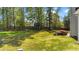 Lush backyard with mature trees, a playhouse, and outdoor seating around a fire pit at 3308 Eden Grove Rd, Fuquay Varina, NC 27526