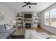 Inviting living room with a stone fireplace, floating shelves, ceiling fan, large window, and hardwood floors at 3308 Eden Grove Rd, Fuquay Varina, NC 27526