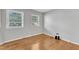 Bright bedroom with hardwood floors, two windows, and neutral gray walls at 704 Sunnybrook Rd, Raleigh, NC 27610