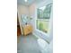 Sunlit bathroom featuring gray tile floors, a wood vanity, and a window overlooking the yard at 72 Beverly Dr, Durham, NC 27707